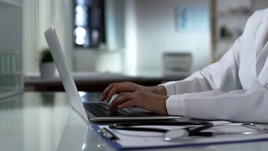 a doctor typing patient's information on the laptop